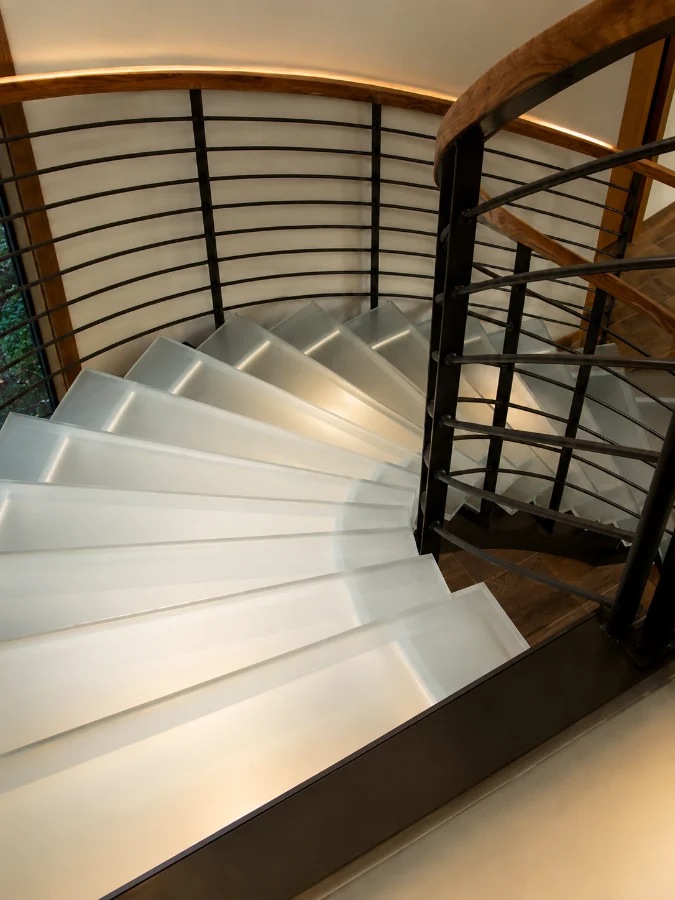 Spiral staircase with frosted glass treads and a curved railing