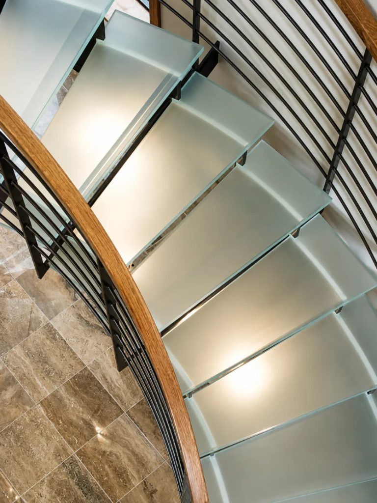 Close-up of frosted glass stair treads on a spiral staircase with a wood handrail